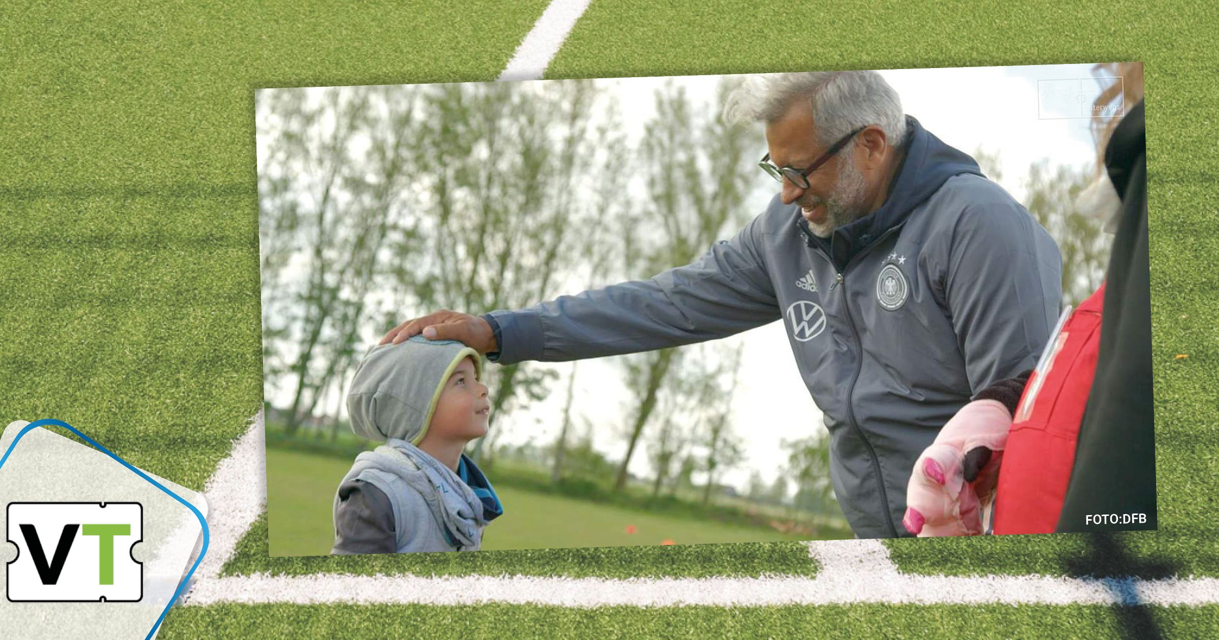 Jimmy Hartwig redet mit einem Jungen auf dem Sportplatz